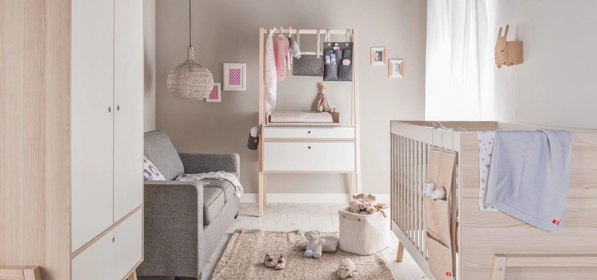 Łóżeczko niemowlęce w stylu boho, z naturalnymi dodatkami i jasną kolorystyką.
